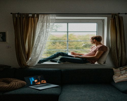 A person taking a short break from their laptop to look out the window